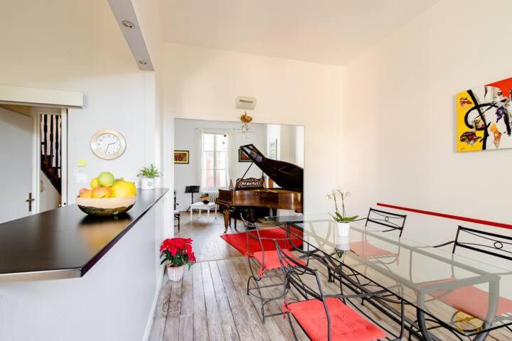 a living room with a glass table and a piano at Gîte de charme Sinfonia in Bergerac