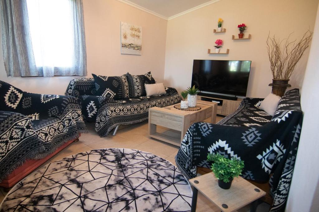 a living room with couches and a flat screen tv at KALLIOPIs HOUSE in Paralia Katerinis
