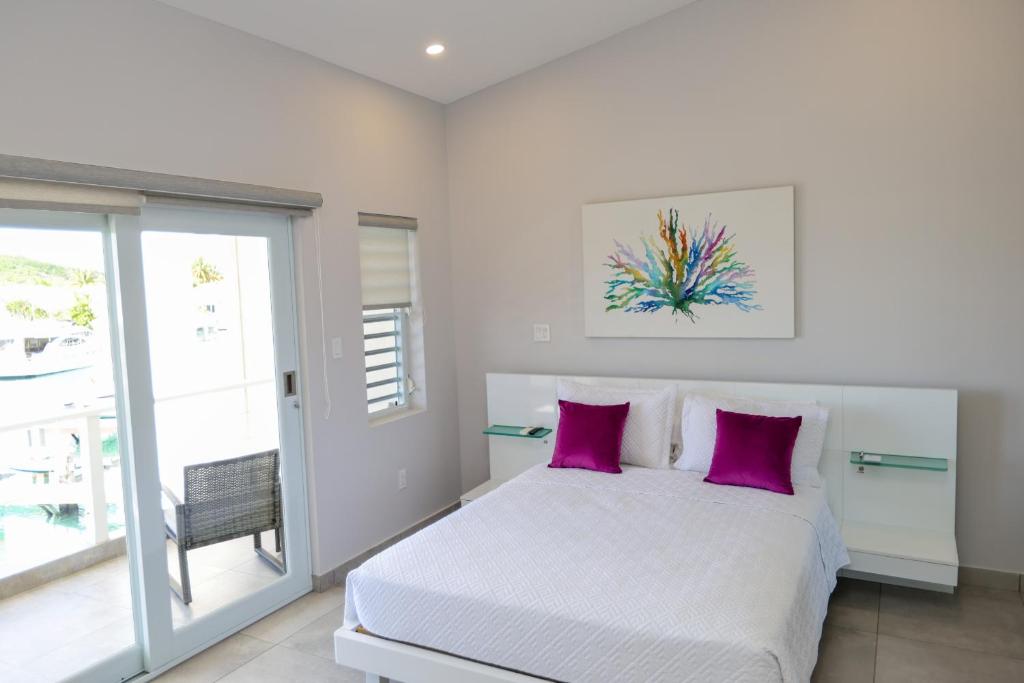 a bedroom with a white bed with purple pillows at 246D South Finger in Jolly Harbour