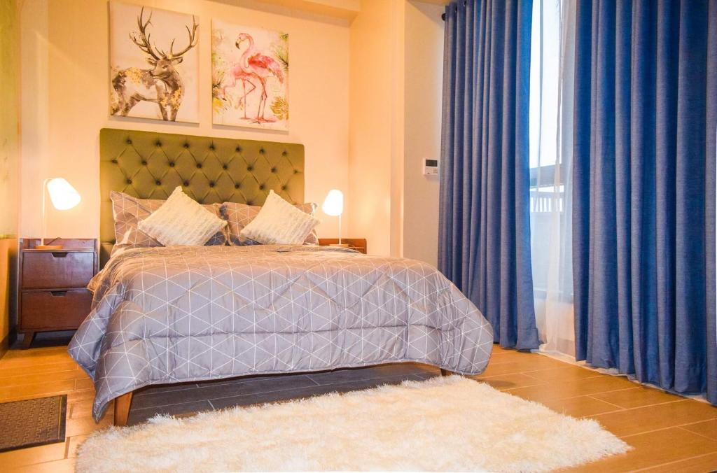 a bedroom with a large bed with blue curtains at Mactan Daily Staycation in Punta Engaño