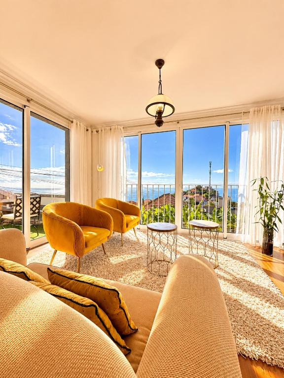 a living room with a couch and chairs and windows at A Velha Casa Caboz in Ponta do Sol