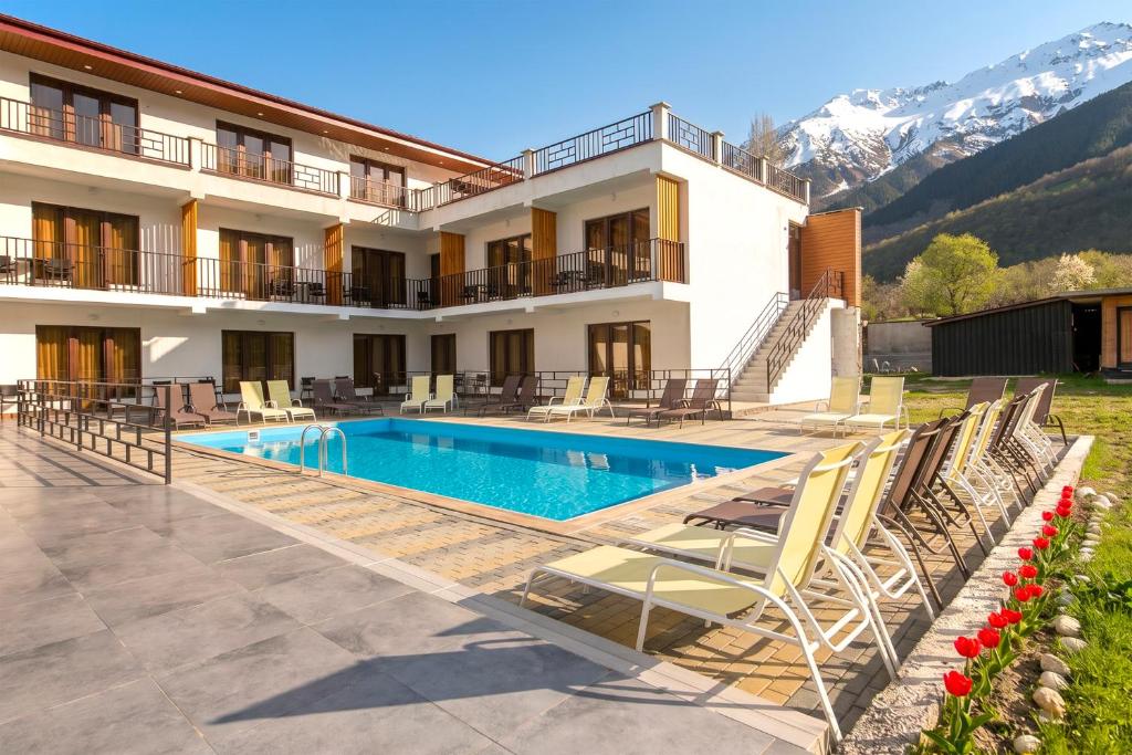a resort with a swimming pool and mountains in the background at Anne's Hotel in Mestia in Mestia