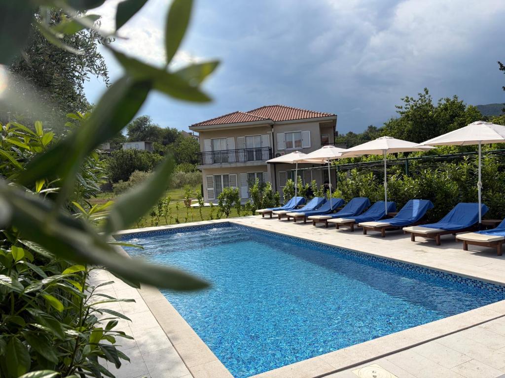 a swimming pool with lounge chairs and a house at Vila CarpeDiem in Herceg-Novi