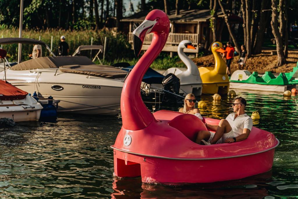 two people in a pink swan boat in the water at Houseboat - Hotel Ukiel Wellness & SPA in Olsztyn