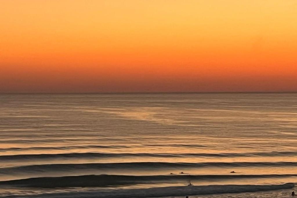 an orange sunset over the ocean with waves at Lacanau-Océan Triplex Front de mer in Lacanau-Océan