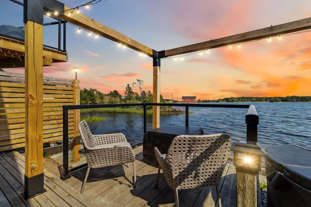 a deck with two chairs and a table on the water at Private Oceanfront Suite Hot Tub & Fireplace in Lunenburg