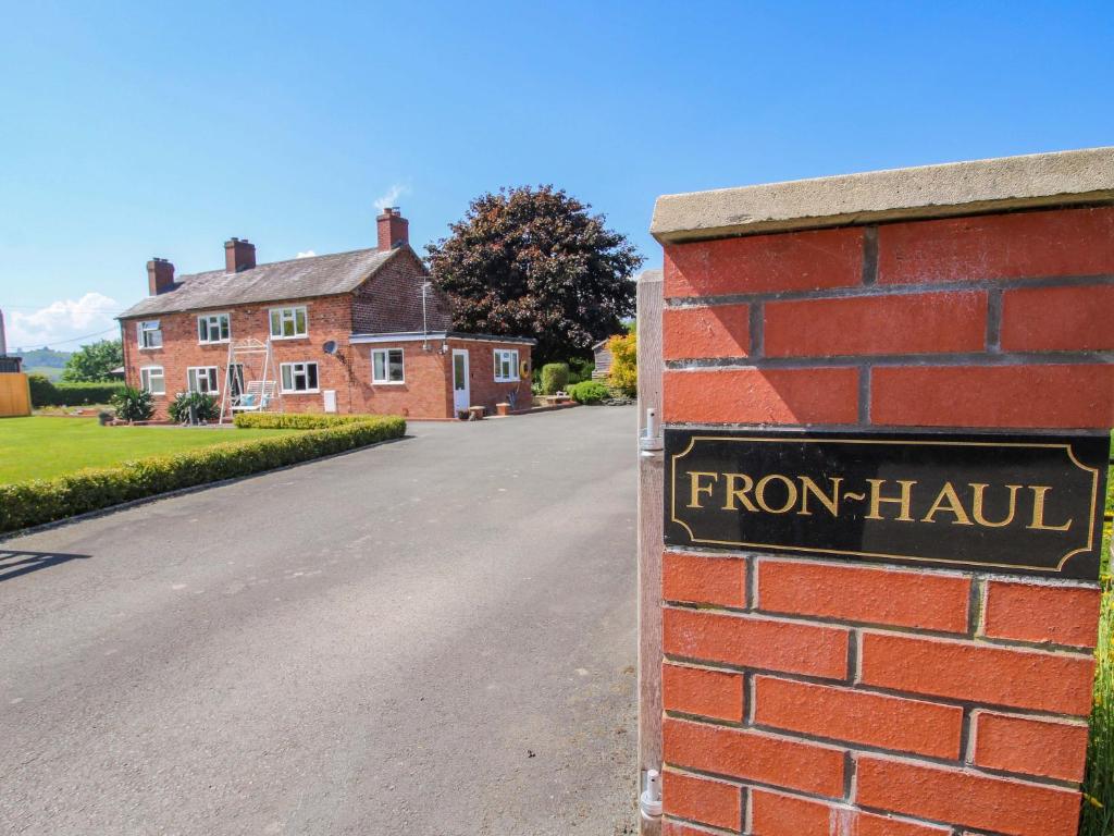 a brick wall with a sign in front of a house at Fron-Haul in Llansantffraid-ym-Mechain
