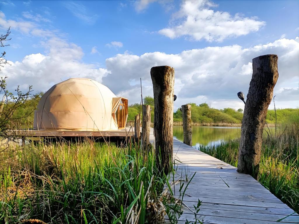 a tent on a dock next to a body of water at Les Gîtes De Robin'son in Foulcrey