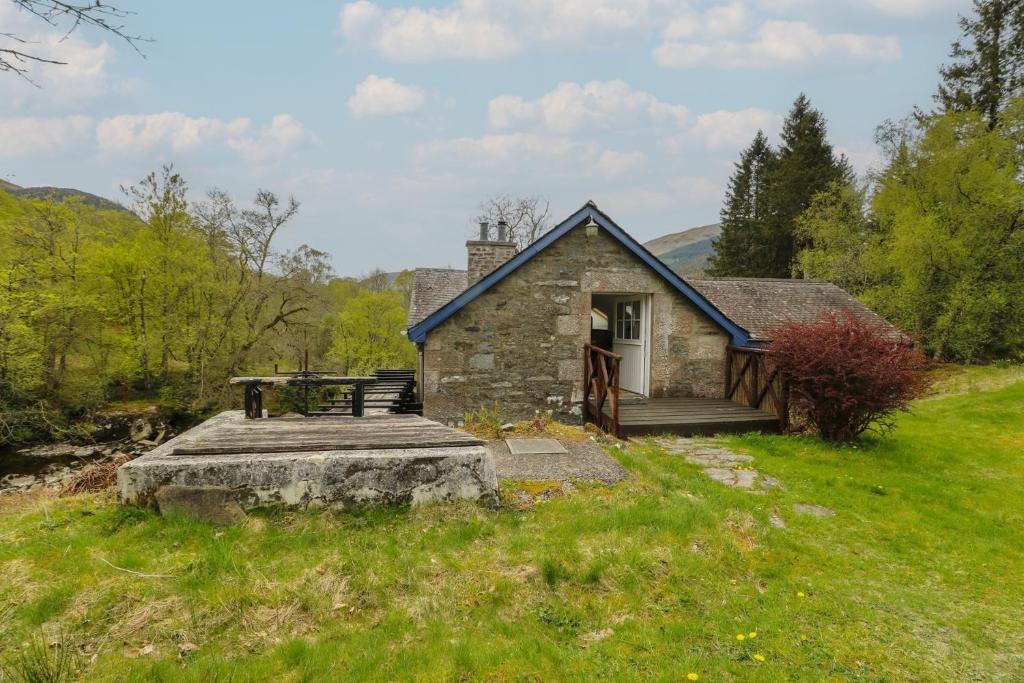 a stone cottage with a picnic table in a field at Culearn Mill in Lochearnhead