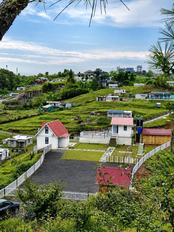 a small village with a white fence and houses at Cozy corner Homestay in Mawphlang