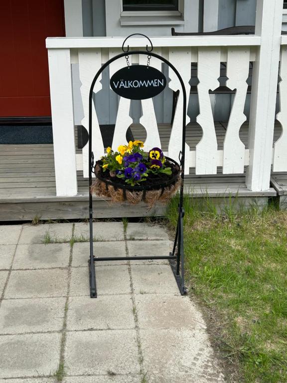 a plant stand with a basket of flowers on a porch at Kukkolaforsen 160 in Haparanda