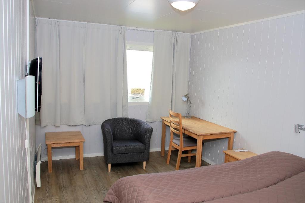 a bedroom with a bed and a desk and a chair at Havøysund Hotell & Rorbuer in Havøysund