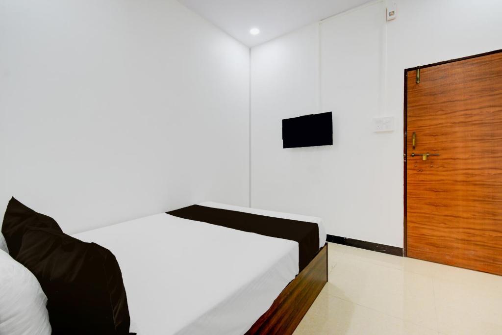 a bedroom with a bed and a wooden door at Super Hotel O P3 Thumkunta in Hyderabad