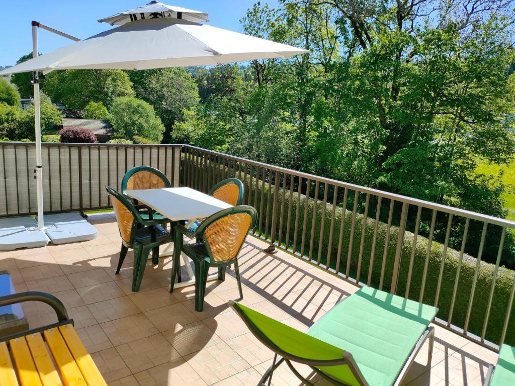 a patio with a table and chairs and an umbrella at Gîte 1805 Montagnes du Jura avec Spa et Sauna classé 3 étoiles in Foncine-le-Haut