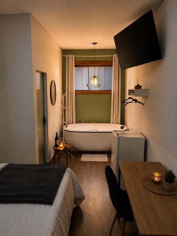 a bedroom with a bed and a bath tub and a table at Hotel Chão Mineiro in São Thomé das Letras