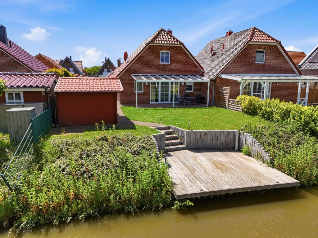 a house on a river with a wooden dock at Friesenperle in Greetsiel