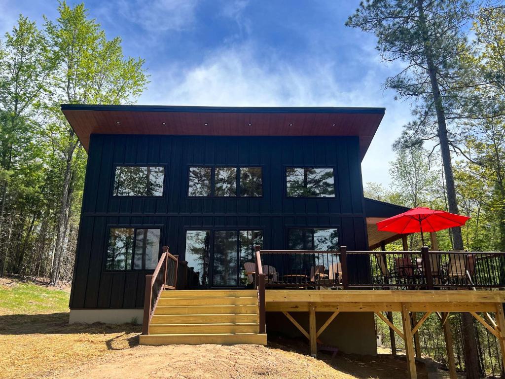 a blue house with a deck and a red umbrella at Towering Pines Cottage in Saint Germain