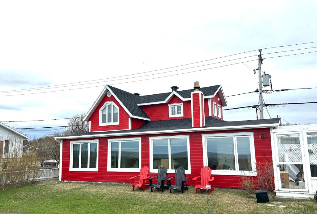 a red house with two chairs in front of it at Loft de la mer in Sainte-Flavie