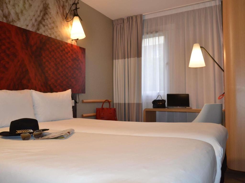 a hotel room with a large white bed with a hat on it at ibis Melun in Melun