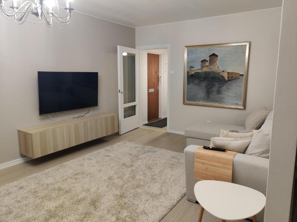 a living room with a couch and a flat screen tv at Room Sonaatti in Savonlinna