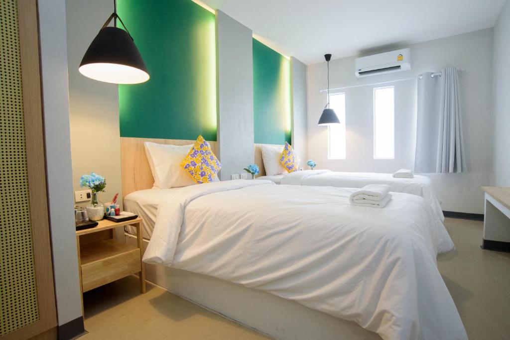 a bedroom with two white beds and a green wall at MINI Plume Minburi in Min Buri