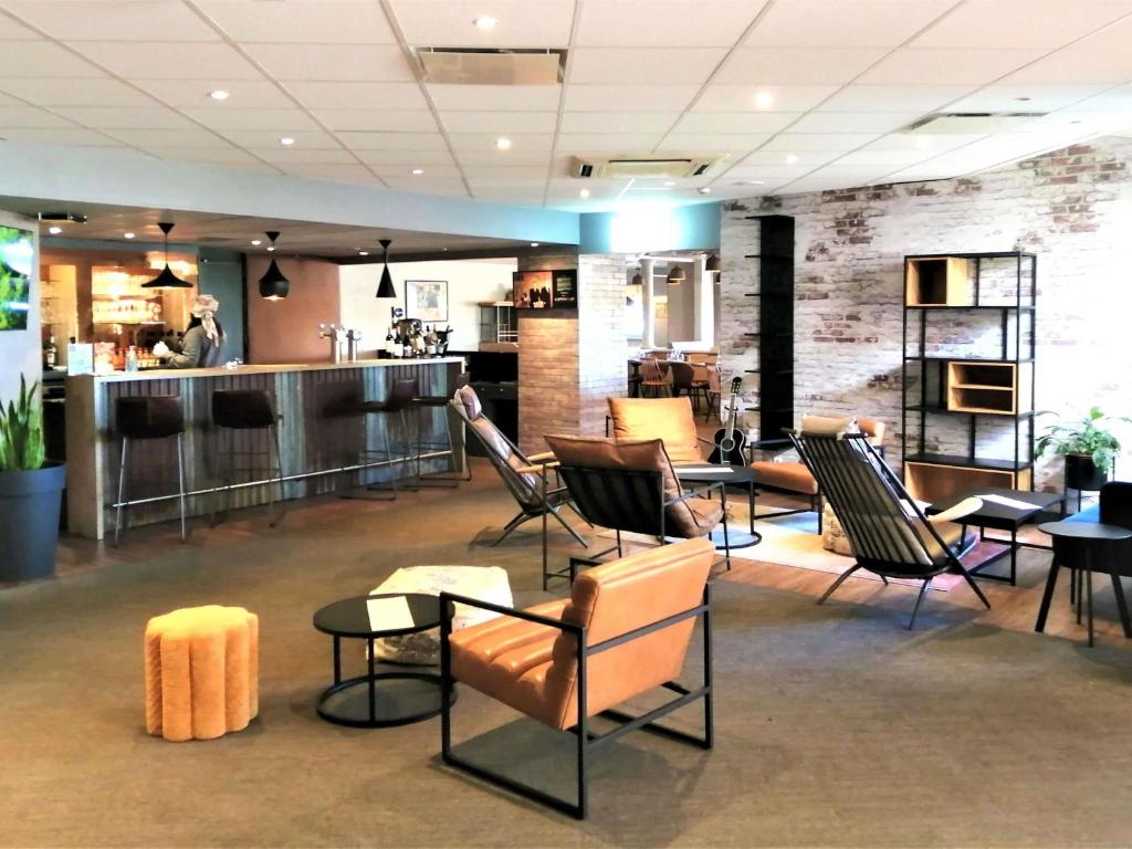 a lobby with chairs and tables and a bar at ibis Poitiers Sud in Poitiers