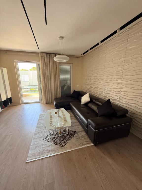 a living room with a black leather couch and a table at Lalzi Vacation Apartment in Lalzit Bay