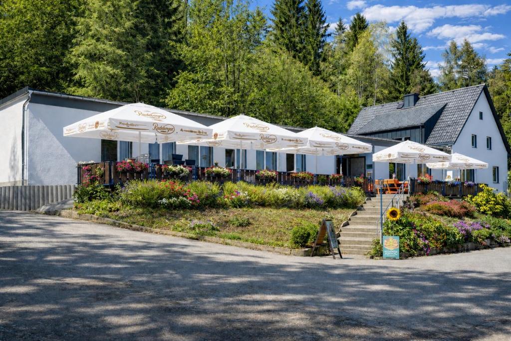 a building with white umbrellas in a garden at Pension und Berggasthaus Am Knochen in Geyer