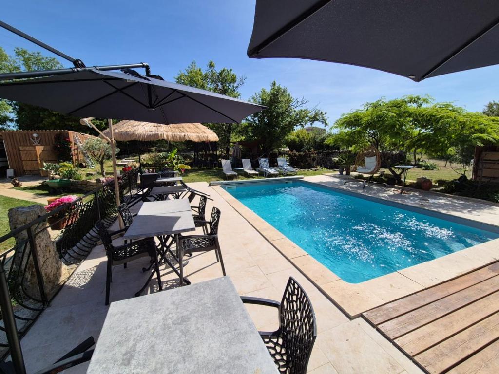 a swimming pool with tables and chairs and an umbrella at Le petit Riyade in Cambayrac