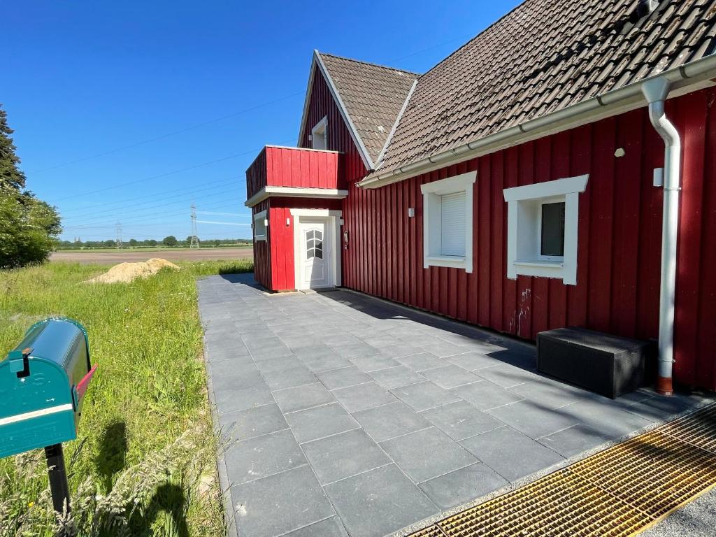 a red building with a sidewalk next to it at Ferienhaus Calle in Bücken
