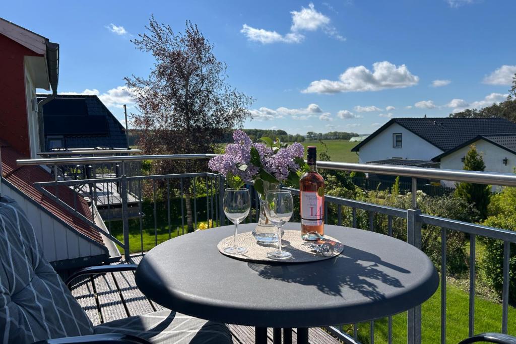 a table with two wine glasses and flowers on a balcony at Ruhige Auszeit zu zweit - Ferienwohnungen auf Usedom für Radfahrer & Strandliebhaber in Loddin