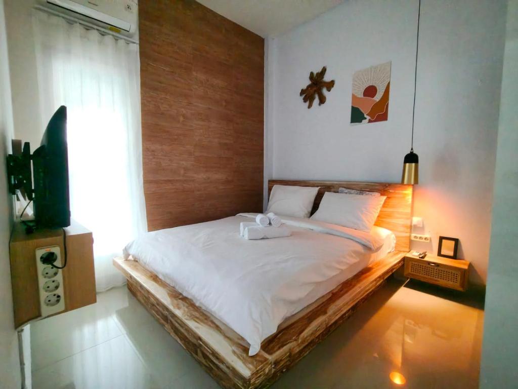 a bedroom with a bed and a television in it at Homestay Omah in Tabanan