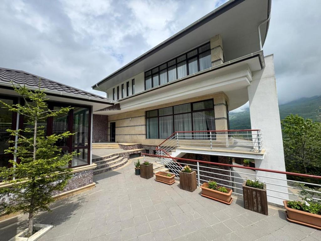 a building with a balcony with potted plants at Panoramic Mountains Hotel Guba in Qırızdǝhnǝ
