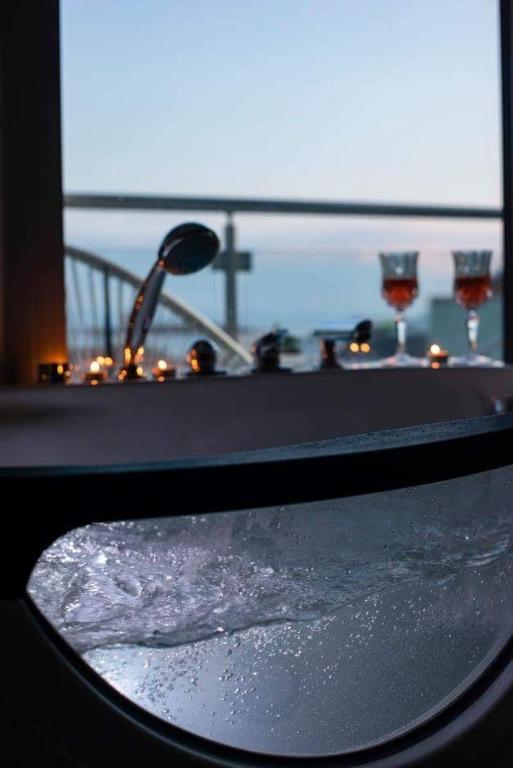 a bath tub filled with water with wine glasses at Lena Apartments Potos Thassos in Potos
