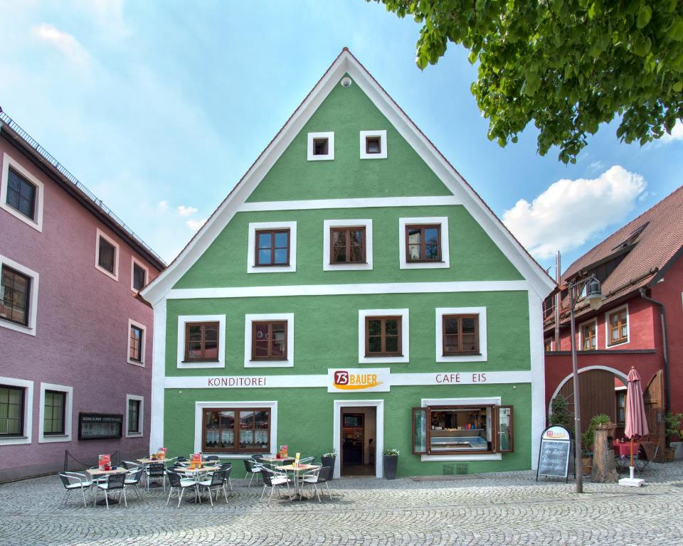 un edificio verde con mesas y sillas delante de él en BAUER Gästezimmer, en Kipfenberg