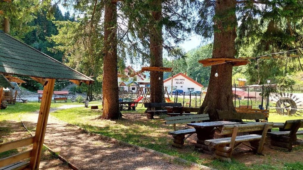 a group of picnic tables in a park with trees at Eko park Jelići in Jelići