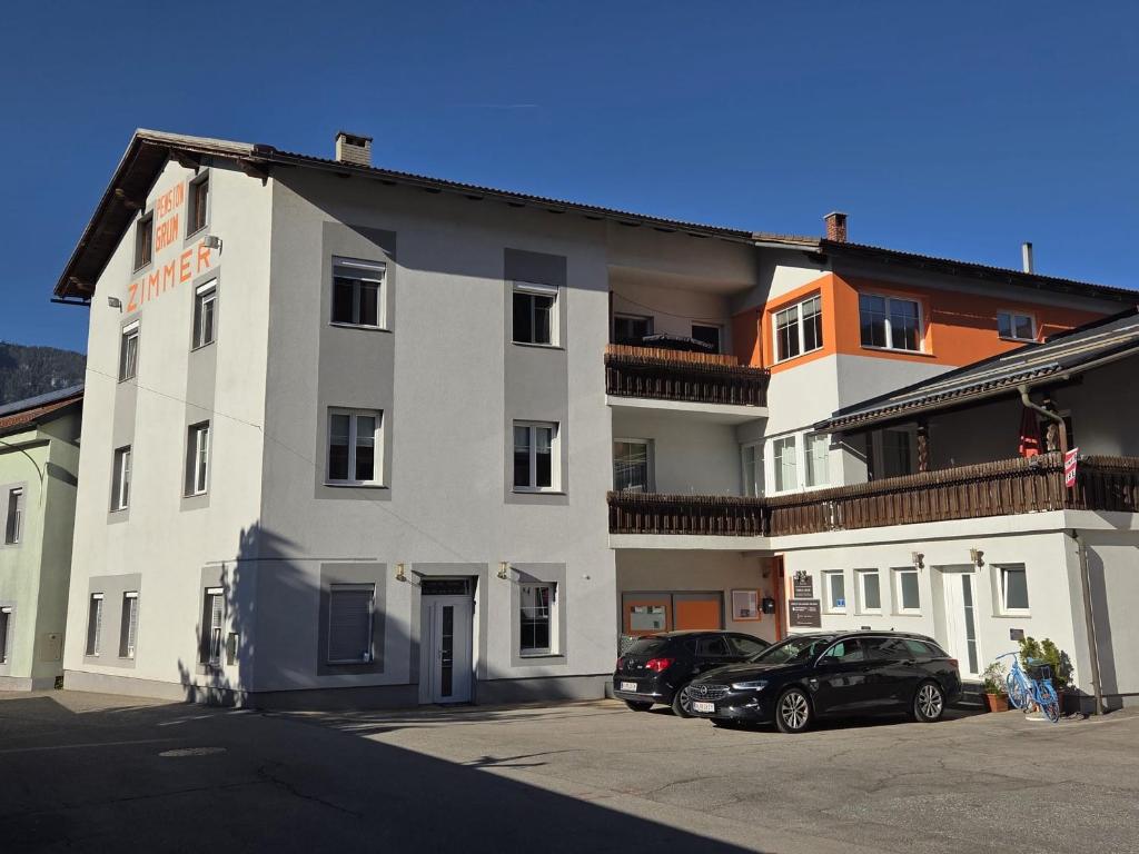 a white building with cars parked in front of it at Pension Grum in Arnoldstein