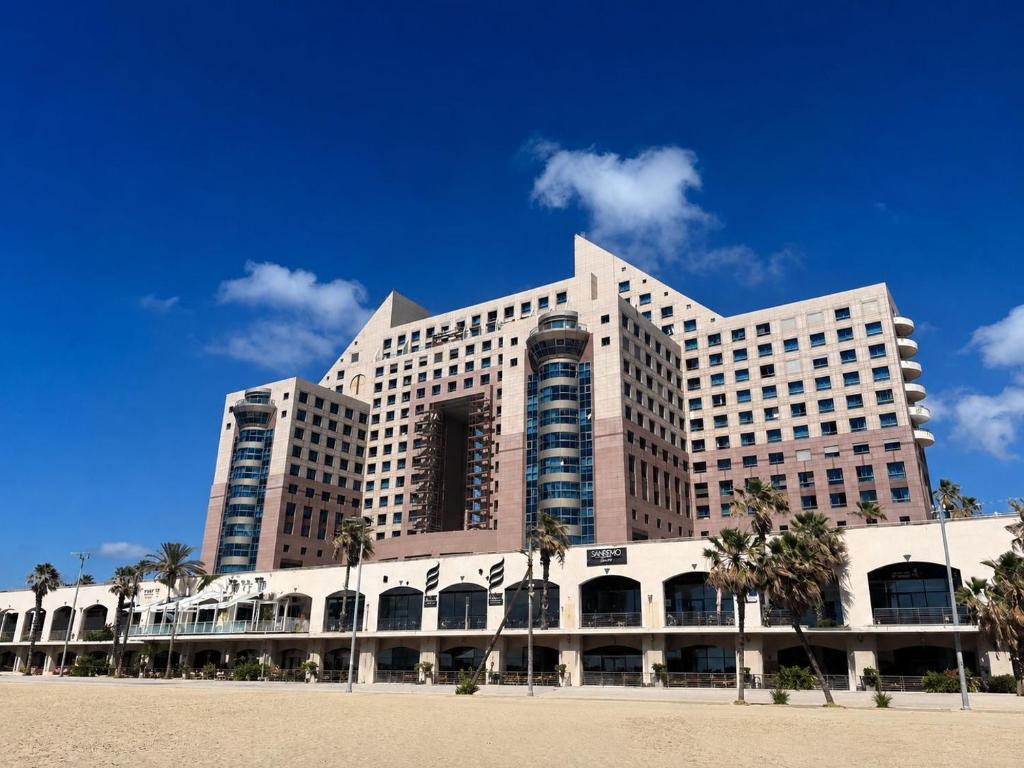a large building with palm trees in front of it at Azure apartments Haifa in Haifa
