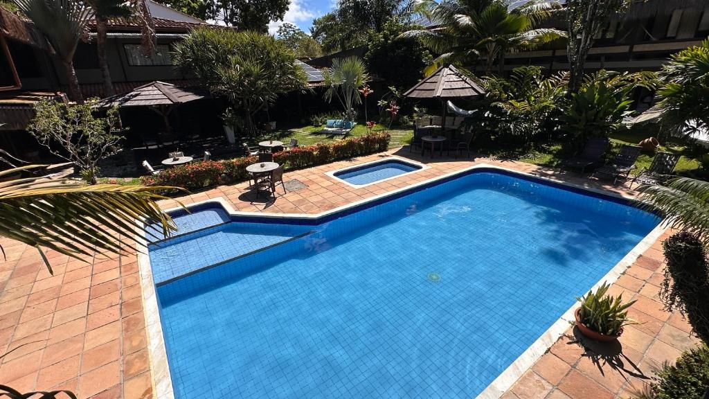 a large swimming pool in a yard with a resort at Pousada Saudosa Maloca in Arraial d'Ajuda
