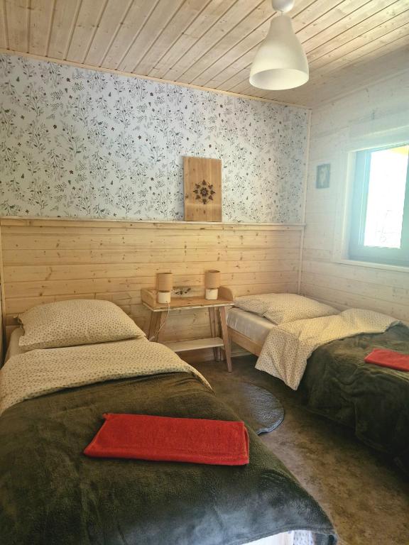 a room with two beds and a table in it at Osada Bura Polana - drewniane domki z sauną in Ujsoły