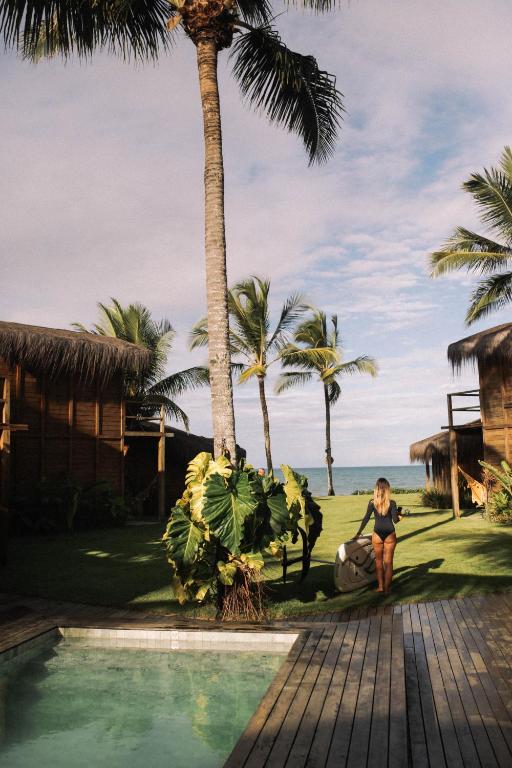 a woman kneeling next to a swimming pool next to the beach at Pousada D'Oxum Caraíva in Caraíva