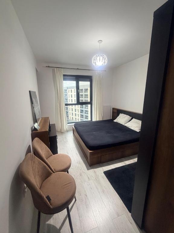 a bedroom with a bed and a chair and a window at Modern Flat Near Bucharest in residence in Dobroeşti