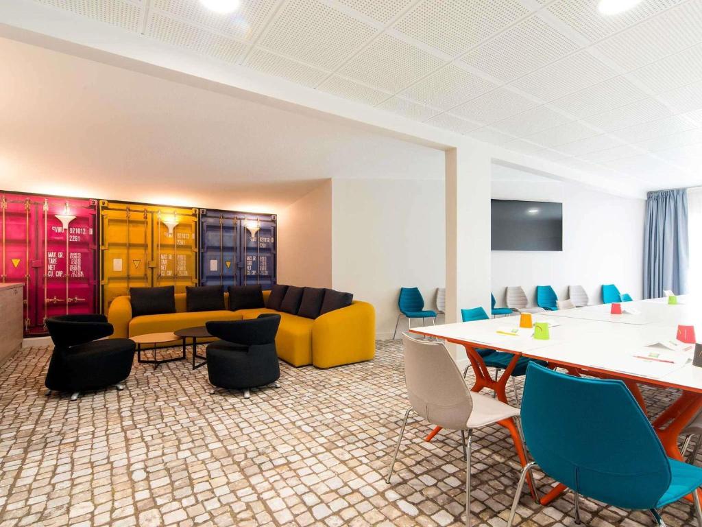 a room with a couch and a table and chairs at ibis Styles La Rochelle Centre Vieux Port in La Rochelle