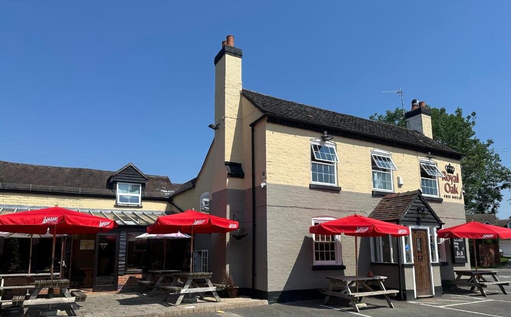 a building with tables and red umbrellas in front of it at ROYAL OAK in Kinnersley