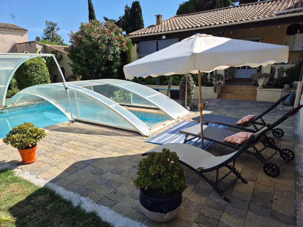 a chair and an umbrella next to a pool at Les Lauriers in Espondeilhan