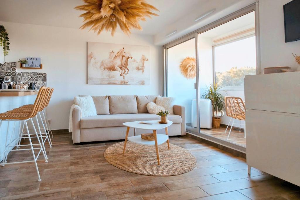 a living room with a couch and a table at Sable & Pampas - Meublé de Tourisme 5 étoiles - Vue Panoramique & Terrasse - Climatisation - Plage à 200m in Carnon-Plage