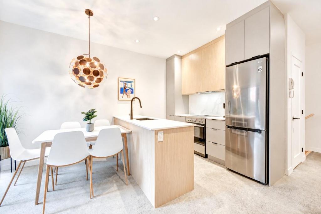 a kitchen with a table and chairs and a refrigerator at Jolie Condo Great Location 2BD presented by TripMontreal I in Montreal