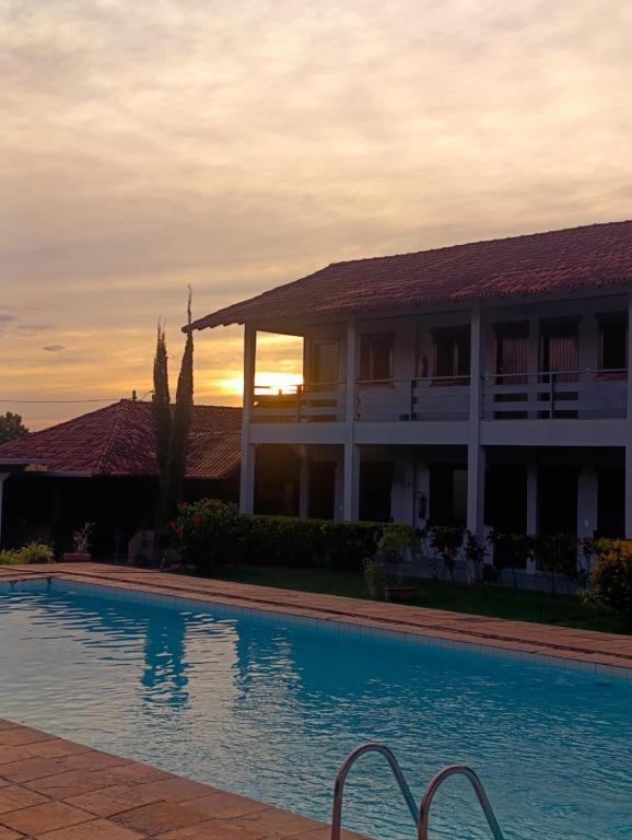a hotel with a swimming pool in front of a building at Marina's Pousada in Pasto da Mata