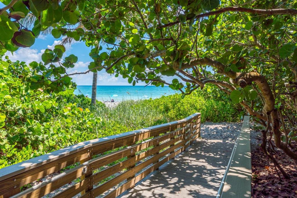 a wooden path to the beach with the ocean in the background at ON The Beach Juno! 3-Top Rated Villa! in Juno Beach