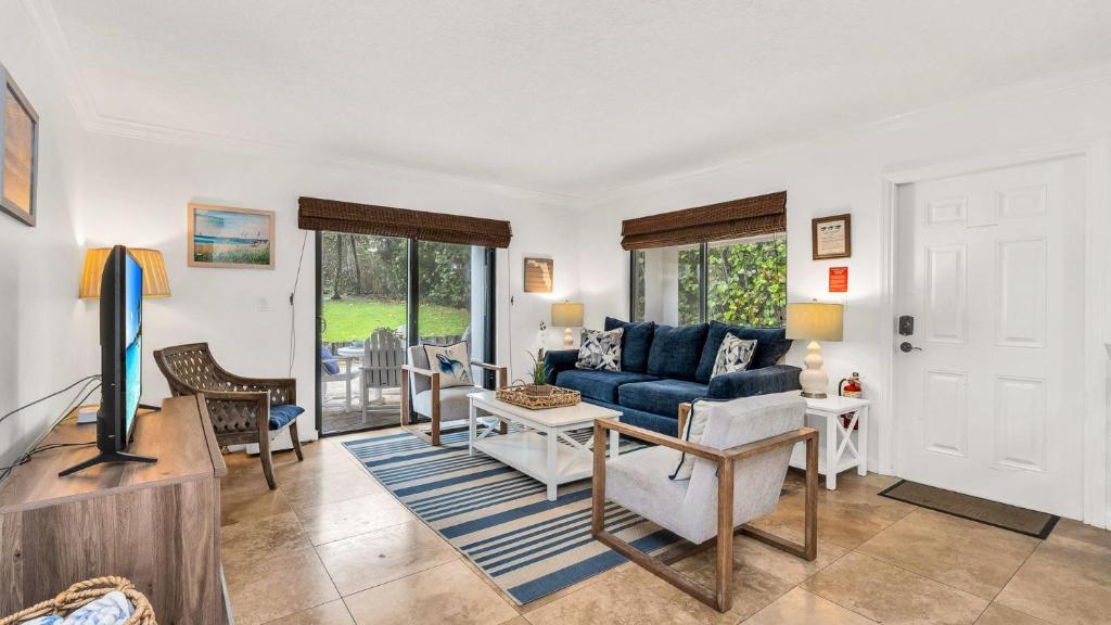 a living room with a blue couch and a tv at Juno Beach Seaside Escape I Steps from the Ocean! in Juno Beach